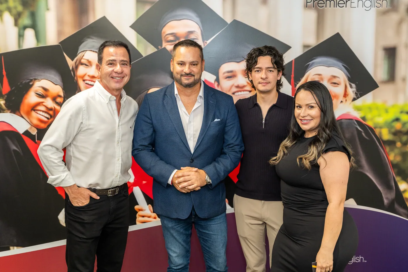 Cuatro invitados posan ante un mural de Premier English durante la inauguración